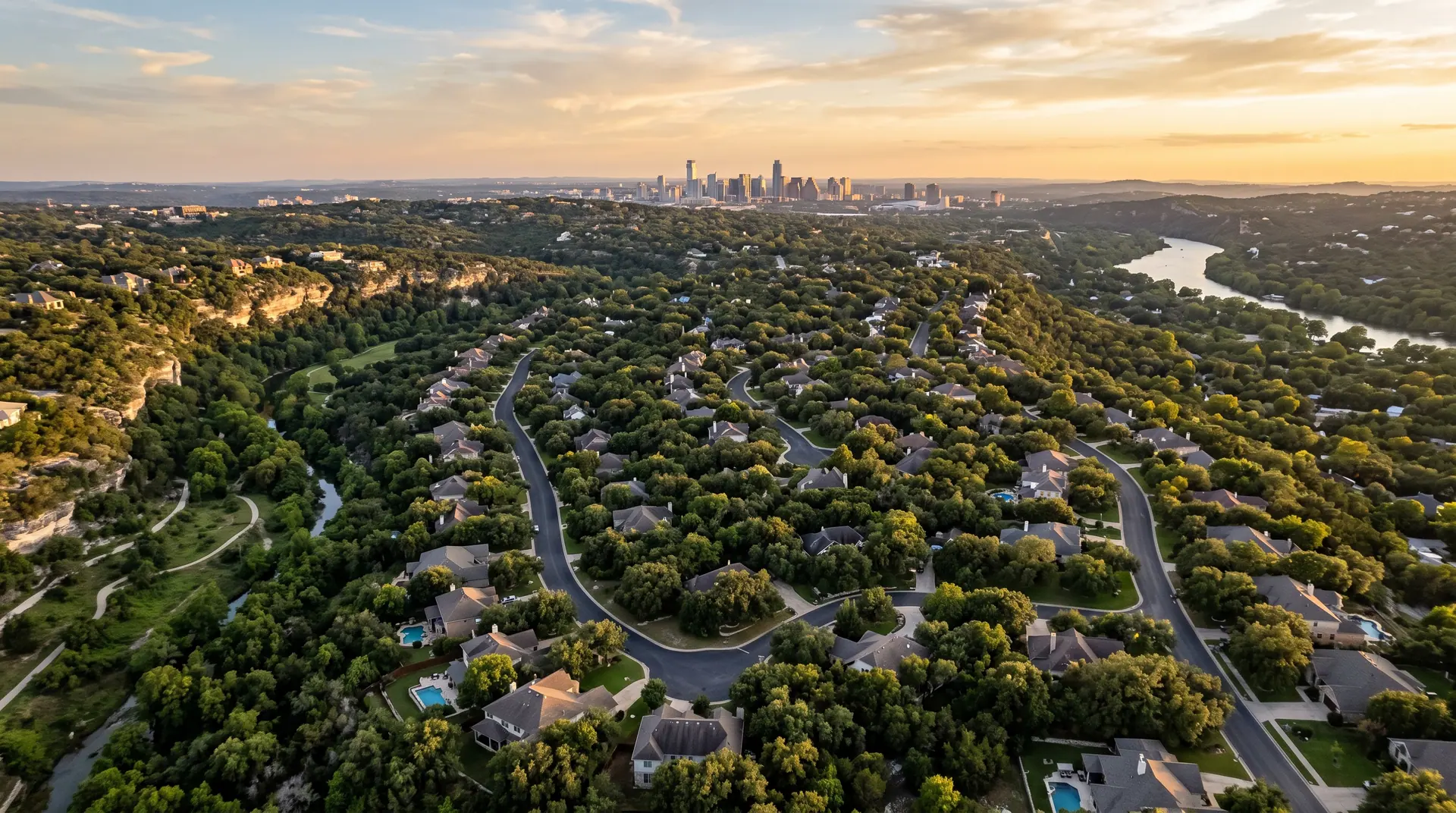 Aerial view over an established Austin hill country neighbourhood with dense live oak canopy at golden hour